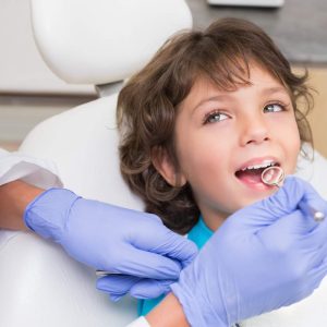 pediatric-dentist-examining-little-boys-teeth-in-the-dentists-chair